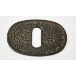 A Japanese iron tsuba, oval form cast with calligraphy mark, 9cm wide.