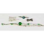 A silver tie brooch, a silver bow brooch, and a green glass necklace.