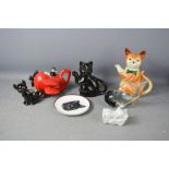 A group of ceramic cats and three teapots.