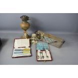 A box of silver plated spoons / knives, candle holder, brass lamp.