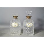 A pair of cut glass and silver collared decanters with gin and Scotch ceramic tags.