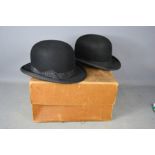 Two bowler hats in a box.