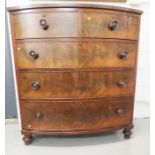 A Victorian flame mahogany bow front chest of three long and two small drawers, with turned knobs