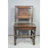 An 18th century oak hall chair, with panel back and bobbin turned legs and stretchers.