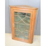 A George III glass fronted oak corner cupboard, with key.