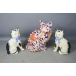 A pair of Victorian ceramic cats (one A/F) and a ceramic cat decorated in a floral pattern.