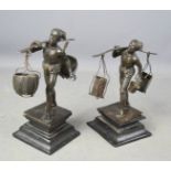 A pair of bronzed metal figurines of fisherman holding baskets, raised on wooden plinths, 20cm