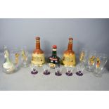 A group of Bells Whisky Wade bottles, retro shot glasses, and a set of retro beer glasses