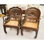 A pair of Chinese zitan wood armchairs, carved to the back with bats and auspicious symbols, caned