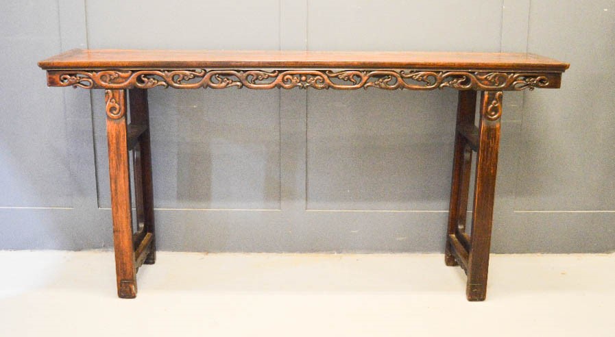 A large hardwood altar table, carved and pierced to the sides, 104 by 210 by 45cm.