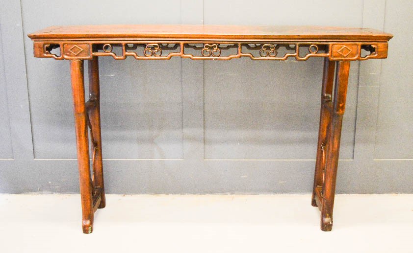 A large hardwood altar table, carved and pierced to the sides, 106 by 176 by 41cm.