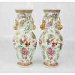 A pair of Chinese famille rose vases, modelled with dogs of fo, gilded highlights, 23cm high.
