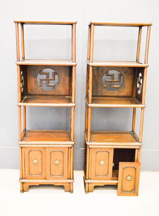 A pair of Chinese display stands / wotnots, with panels pierced with Buddhist symbol of peace, and