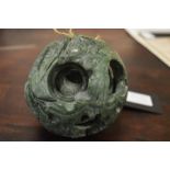 A Chinese carved green soapstone puzzle ball, 10cm diameter.