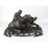 A fine Chinese carving of a water buffalo on stand, with figure riding on its back.