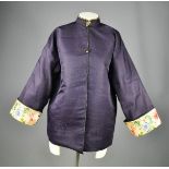 A Chinese silk ladies jacket in dark blue, with yellow lining, the sleeve panels embroidered with