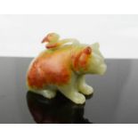 A Chinese Song Dynasty carved celadon coloured jade bear with man to his back, with rust coloured