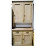 A tall antique pine kitchen cupboard on chest, with ceramic handles, the lower cupboard having two