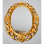 A giltwood oval wall mirror, with scrollwork border, 78 by 58cm.