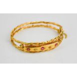 A 9ct gold bangle set with pink rubies, 8.9g.