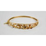 A 9ct gold bangle, pierced floral works set with garnets, 13g.
