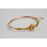 A 9ct gold bangle with seed pearl starburst to the centre, 6.3g.