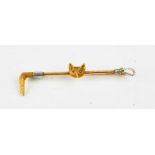 A yellow metal brooch in the form of a fox head and whip, the fox head inset with ruby eyes.
