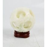 A Chinese hand carved white jade puzzle ball, with stand.