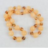 An amber necklace composed of large cloudy amber graduated beads interspersed with small clear amber