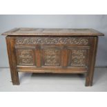 A 17th century oak coffer, with three panelled lid, and carved front, raised on stile feet.