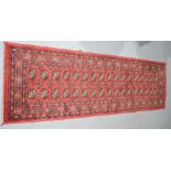 A carpet runner with red ground, traditional elephants paw pattern.