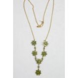 A 9ct gold necklace, set with green glass stones to form flower heads.