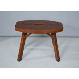A wooden dark stained stool, with oval shaped top.