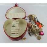 A group of costume jewellery including ten rings, in a red heart form jewellery box.