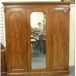 Victorian mahogany triple wardrobe with moulded pediment above panelled doors enclosing hanging