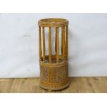 Turned wood circular umbrella stand with caned panels.