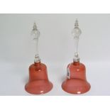 Two cranberry glass hand bells (both lacking clappers), the clear glass handles with ball knop