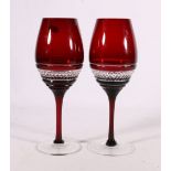 A pair of John Rocha Waterford ruby glass wine glasses.