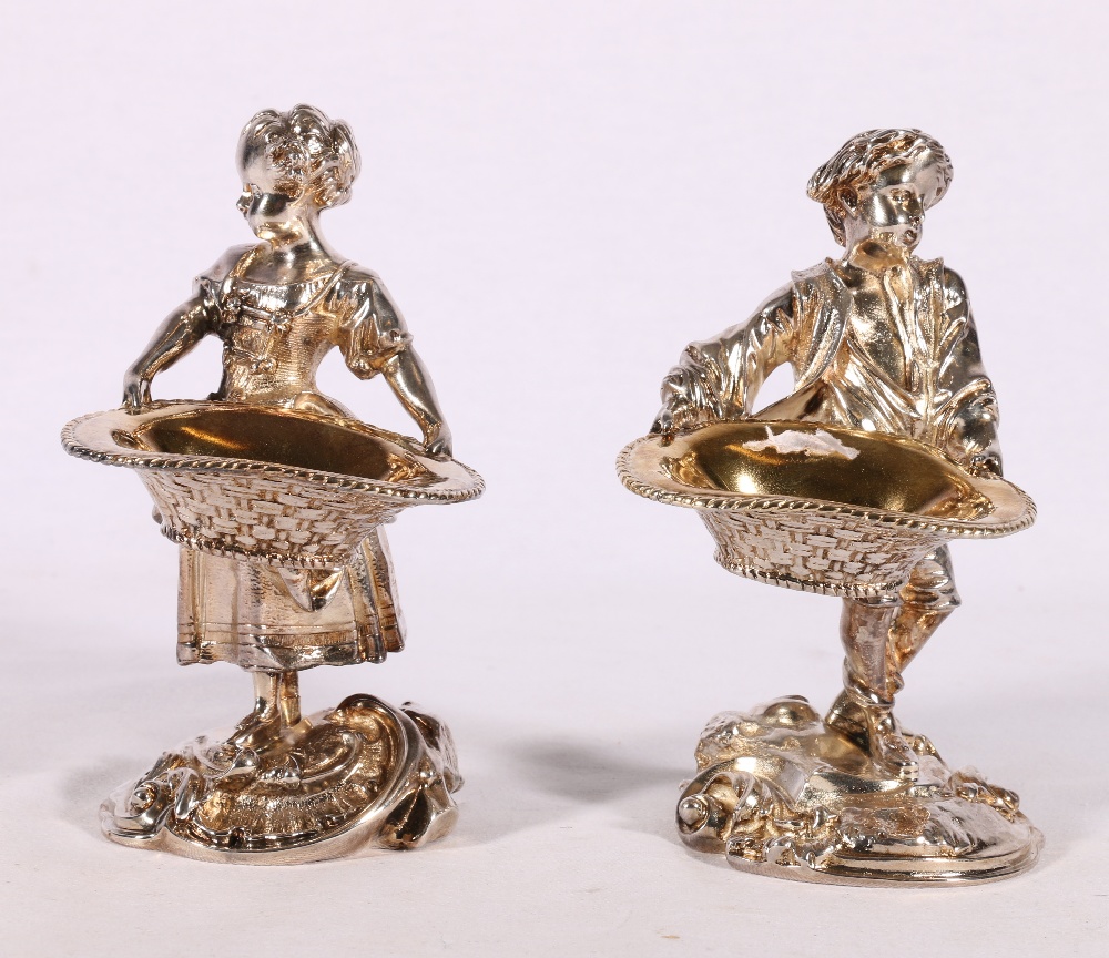 Pair of cast white metal figures modelled as a boy and girl holding baskets possibly as table salts,
