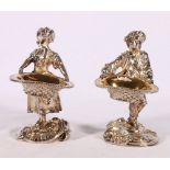 Pair of cast white metal figures modelled as a boy and girl holding baskets possibly as table salts,