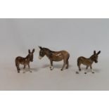 Three Beswick figures: Donkey, no. 1364B, 2nd version, gloss, 11cm high and two x Donkey Foal, no.