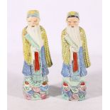 Pair of 20th Century Chinese famille rose figures of sages in traditional robes carrying scrolls, 21