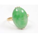 Chinese jadeite ring, oval cabochon approx. 16mm x 11mm x 4mm in gold. Size 'O'.