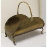 Brass log holder of curved form with swing handle and four scroll feet.