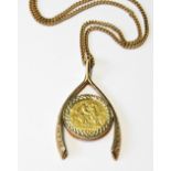 9ct gold pendant modelled as a wishbone enclosing a detachable half sovereign, 1913, 18g.