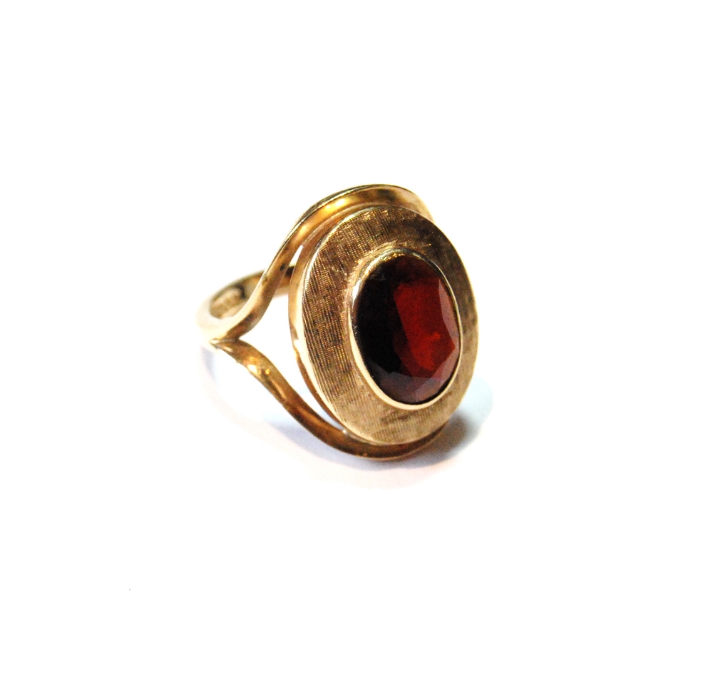 Dress ring with oval garnet on textured band, 9ct gold, 1974, size L.