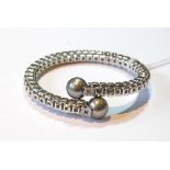 White gold flexible bangle with black pearl and diamond-set terminals, '750', gross 38g.