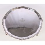 Victorian silver salver with pie crust edge raised on four squat feet, the surface engraved with
