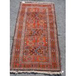 Quchan rug with three H-shaped panels over red ground, rosettes and border, 112cm x 211cm.