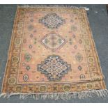 Eastern rug with triple medallions over pink ground, rosettes and border, 157cm x 115cm.